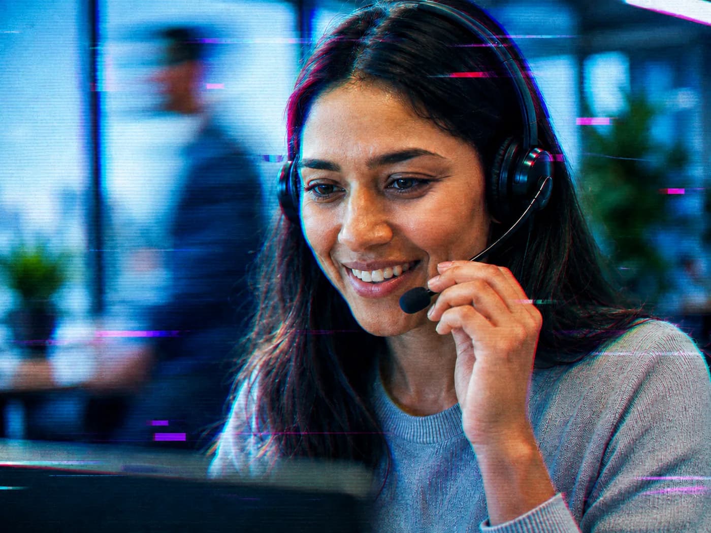 Agente de contact center con diadema, sonriendo frente a su monitor